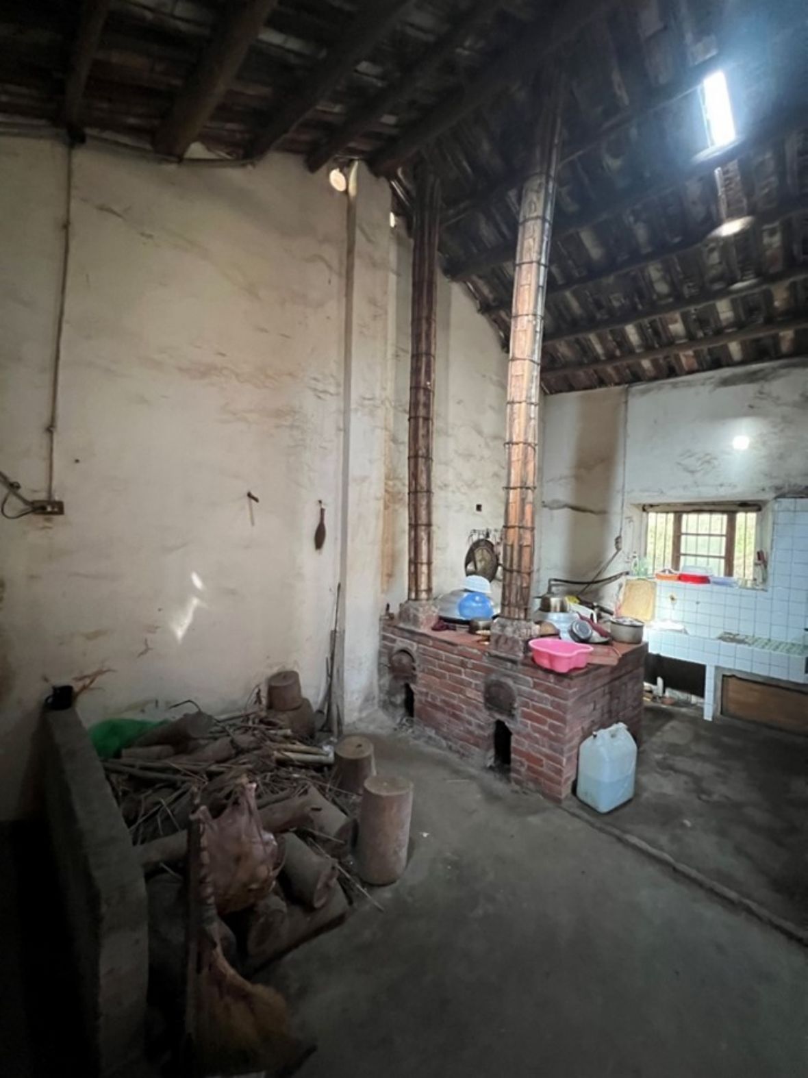 崎頂村仁愛街溫宅的灶爐。屬於典型的新豐客家傳統配置與造型；兩鼎鐵鍋、兩支煙囪、兩口灶門；前有置放薪材場所與矮牆；遠處有貼白色磁磚的獨立的料理與流理台；已不見導井水入廚房的石製水溝槽與儲水水缸，改用自來水管直接供水。