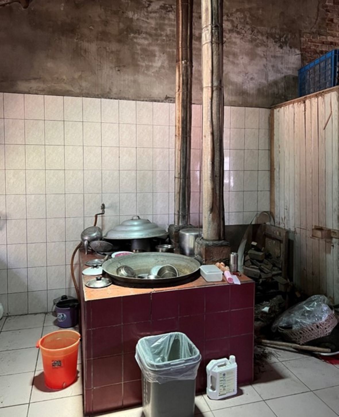 中崙村某宅灶爐。灶爐胴體與右牆之間剛好放置薪材；有充分靈活應用之兩鼎鐵鍋灶臺面；靠牆處有水龍頭直接供兩鼎鐵鍋的用水。