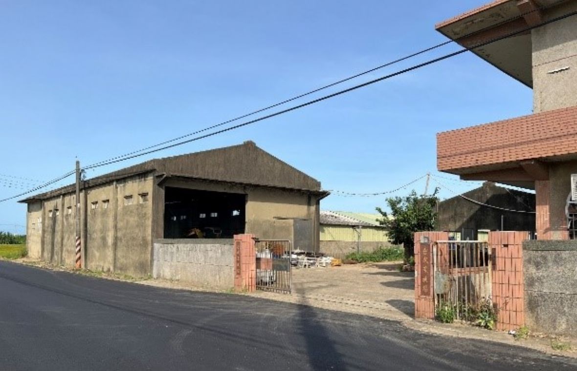 從新竹縣道2-1看緊鄰道路邊的合成牧場飼料倉庫。與其他的倉庫的機能需求相同，於牆體高處開有一排高窗。牆體為加強磚造，柱子外凸牆面，但是內部空間保持與磚牆面平整作法。