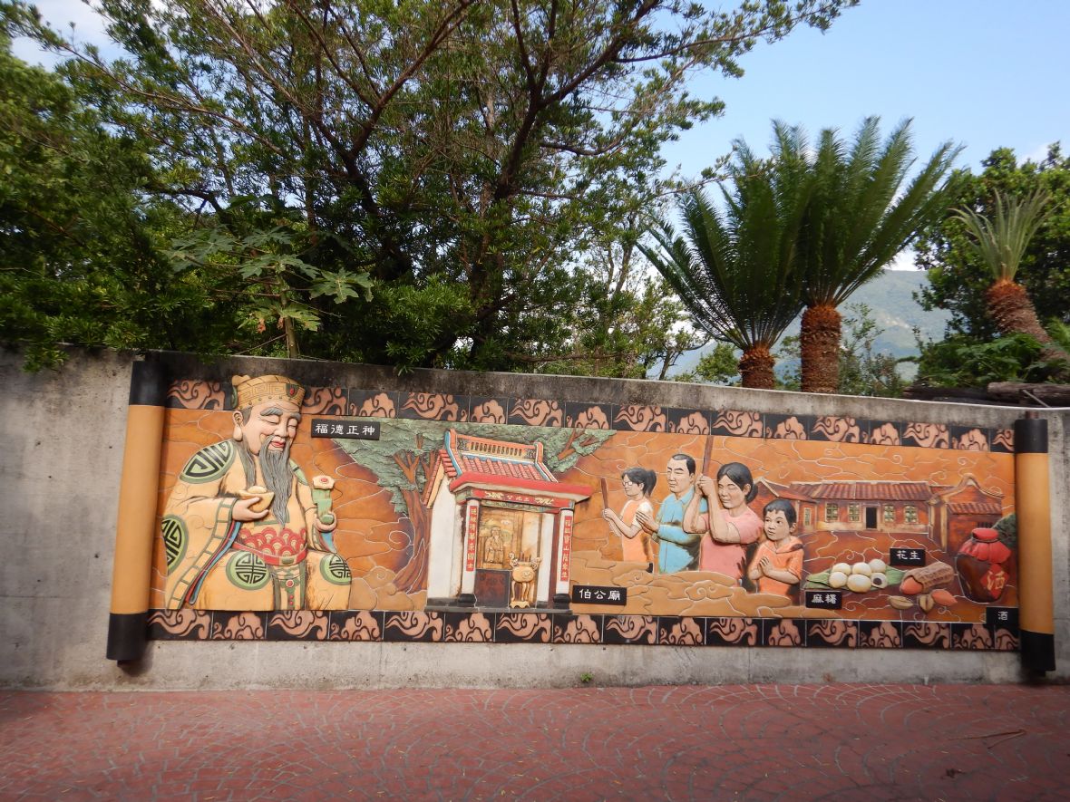 廟埕前的陶板浮雕呈現供奉伯公的習俗